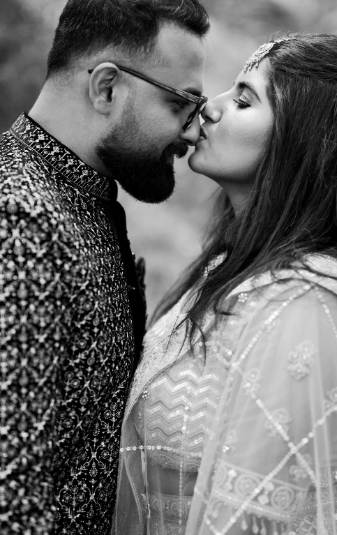 A tender black-and-white photograph of the couple sharing a kiss